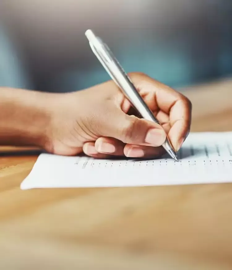 A hand with a pen writing on a paper